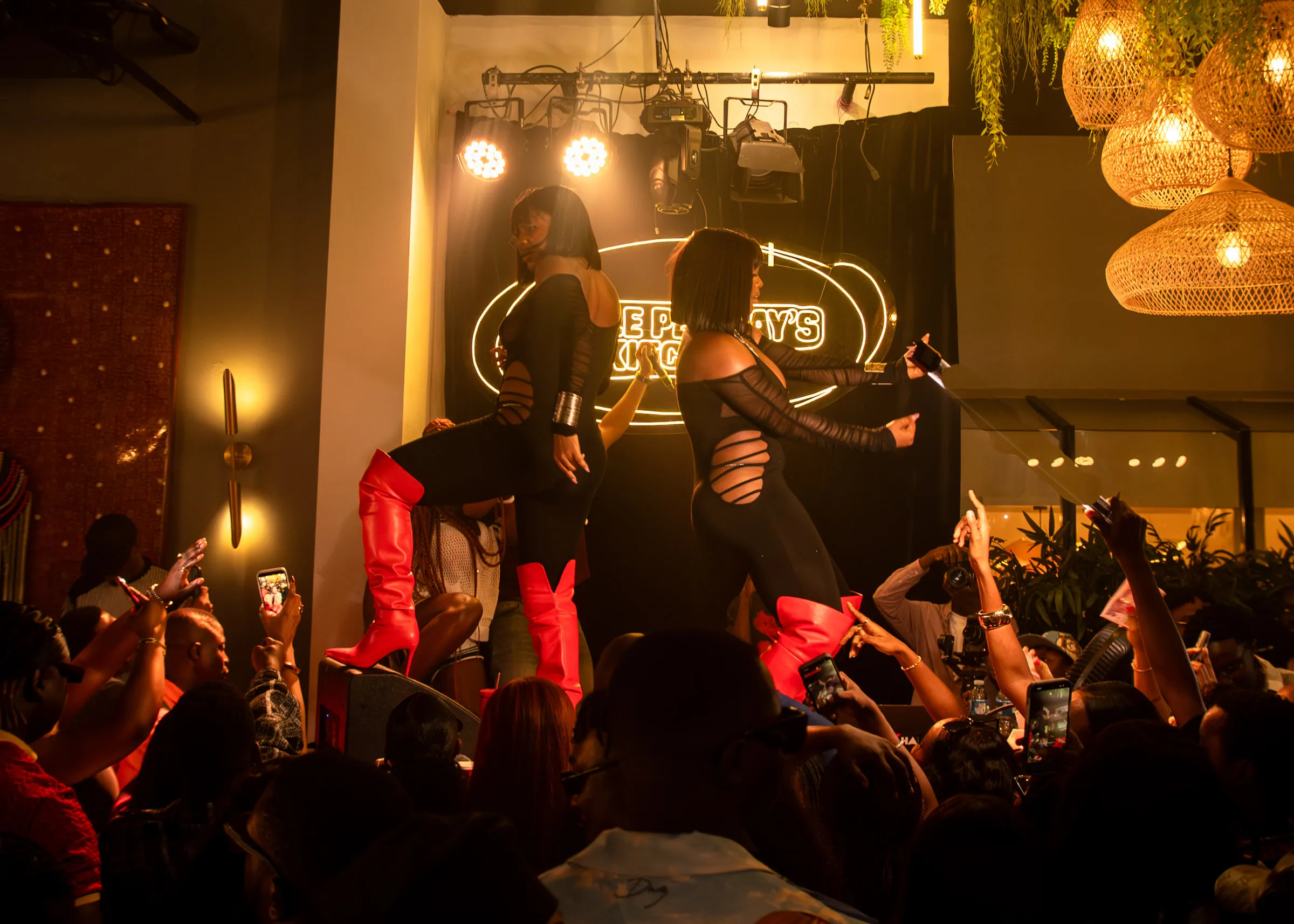 Dancers on the stage under the neon, phones up below